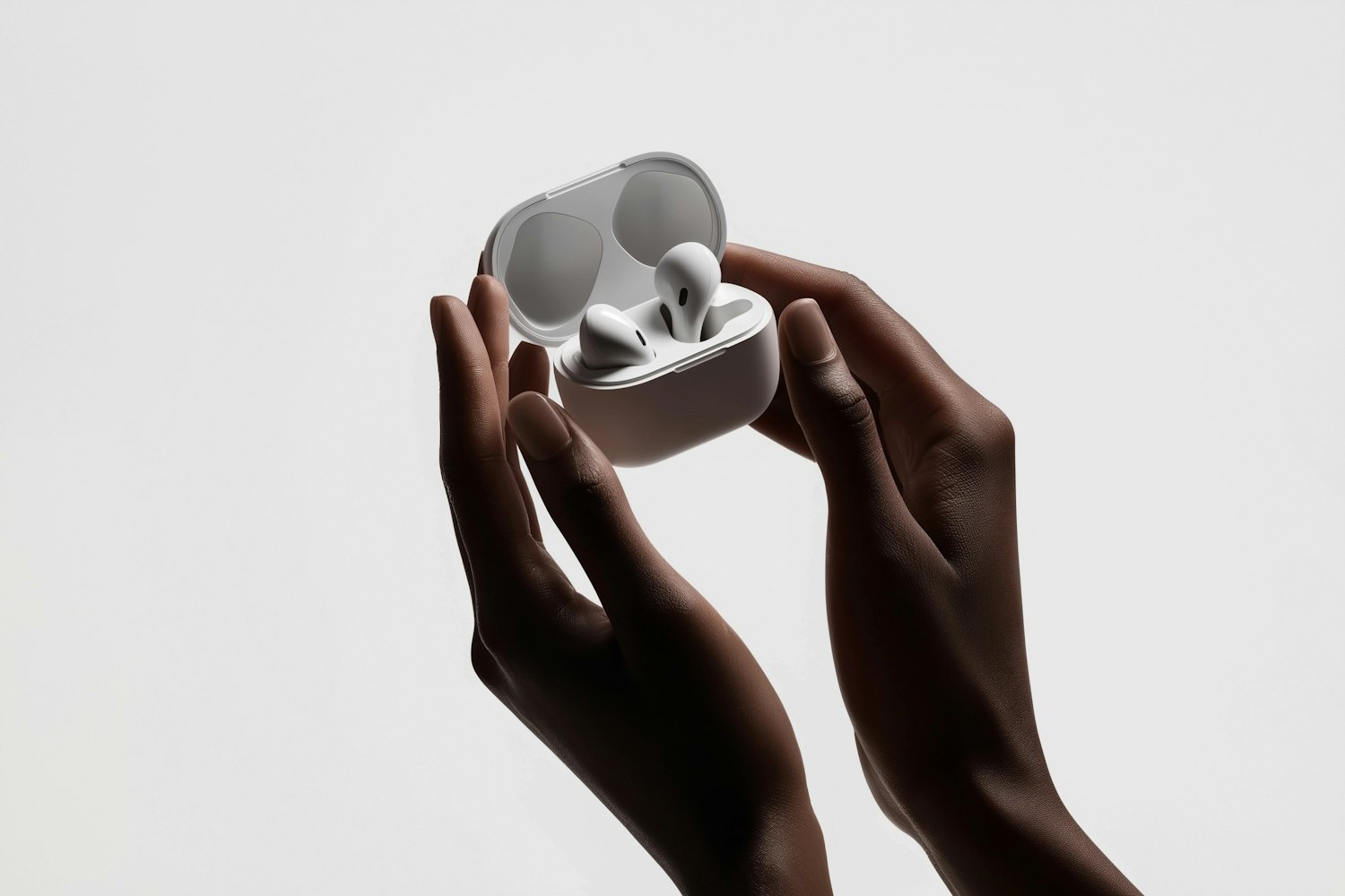 Hands holding an open charging case with white wireless earbuds